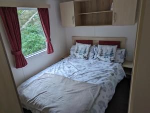 a bed in a small room with a window at The Ocean Pearl caravan number 50 situated on the Cove holiday park in Southwell