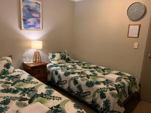 a bedroom with two beds and a clock on the wall at Hamilton Holiday House in Hamilton