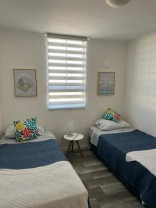 two beds in a room with a window and a table at Departamento full equipado con vista al mar in Caldera