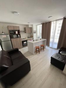 a living room with a black couch and a kitchen at Hermoso Depto Piscina in Rancagua