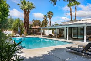 a swimming pool in front of a house with palm trees at The Kasbah in Palm Springs