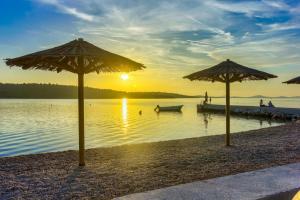 twee parasols op een strand met een boot in het water bij Apartmani Mato in Pirovac