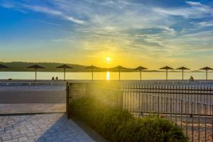 een zonsondergang op het strand met parasols op het strand bij Apartmani Mato in Pirovac