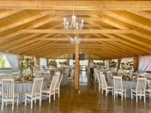 a banquet hall with white tables and chairs and a chandelier at Райский Дворик in Pogreby