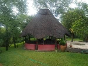 a gazebo with a straw roof in a yard at Adrenaline Lodge and Tours in Livingstone