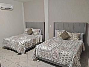 a bedroom with two beds in a room at Tres Migueles, Departamento Alaain, familiar, comodo, cerca de la marina, zona turistica y playa in Cabo San Lucas