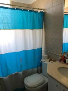 uma casa de banho com uma cortina de chuveiro azul e branco e um WC. em Algarrobo Punta Fraile Hermosa vista a la bahia de Algarrobo em Algarrobo