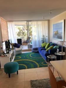 uma sala de estar com um sofá azul e um tapete verde em Algarrobo Punta Fraile Hermosa vista a la bahia de Algarrobo em Algarrobo