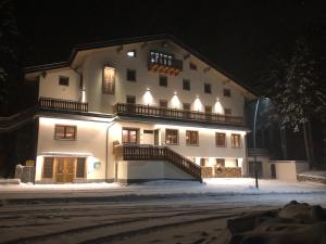 Un grand bâtiment blanc dans la neige la nuit dans l'établissement Hotel I Pionieri, à Abetone