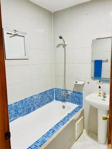 a blue and white bathroom with a tub and a sink at Nouadhibou Guest House in Nouadhibou
