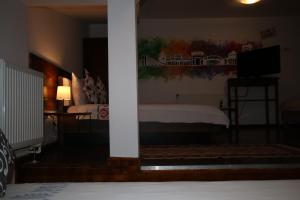 1 dormitorio con 1 cama y TV en una habitación en B&B Duo Caffe Baneasa en Bucarest