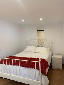 a bedroom with a white bed with a red blanket at Apartamento Sant-Yago in Santiago de Compostela