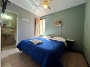 1 dormitorio con cama azul y baño en Hotel cuesta del viento II en San Juan