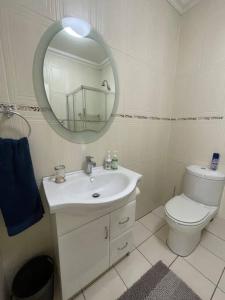 a white bathroom with a toilet and a mirror at Stonehenge Clarens in Clarens