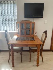 a wooden table with two chairs and a tv at Stonehenge Clarens in Clarens
