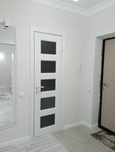 Dieses weiße Zimmer verfügt über eine Tür und einen Spiegel. in der Unterkunft 1-но комнатная квартира в центре Астаны ЖК Sezim Qala 4 in Astana