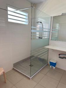 La salle de bains est pourvue d'une douche avec une porte en verre. dans l'établissement Hôtel DOUCE VAGUE, à Sainte-Luce