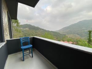 una silla azul sentada en un balcón con vistas en yuvacik kazli bahçe bungalov & taş otel, en Yuvacık