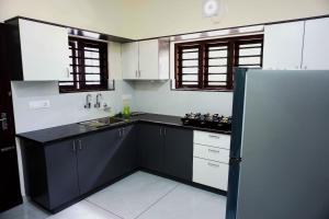 uma cozinha com armários a preto e branco e um frigorífico em PEACEFUL LIVING SUITE II em Cochin