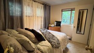 een slaapkamer met een bed met kussens en een raam bij Blue Heron Sanctuary & Serene, river-front cottage in West Linn