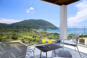 a balcony with a table and chairs and a view of the ocean at OFF White Villas in Vasiliki