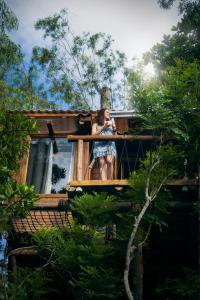 uma mulher de pé na varanda de uma casa na árvore em Itapeva Ecovillage em Torres