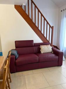 un sofá púrpura en una sala de estar con una escalera en Appart’ chaleureux proche Paris, en Chelles