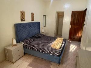 1 dormitorio con cama azul y puerta de madera en Chez papy 2, en Dakar