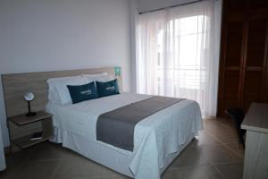 a bedroom with a bed with blue pillows and a window at Ayenda Torre 2 in Apartadó