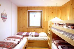 Ce lit se trouve dans un dortoir doté de murs en bois et d'une fenêtre. dans l'établissement CASA DOLOMIA - vista Dolomiti, Dolomiti Affitti, à Cavalese