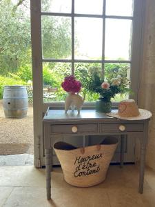 einen Tisch mit einem Fenster mit Blumen und einem Korb in der Unterkunft Le Gaimont Maison d'Hôtes Vouvray in Vouvray