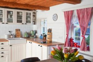 una cucina con armadi bianchi e un tavolo con fiori di Chalupa na Valech a Krompach Altre 37 foto