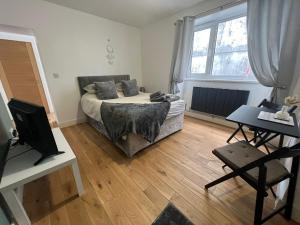 a bedroom with a bed and a desk and a television at Dream Weaver Apartment in Swansea