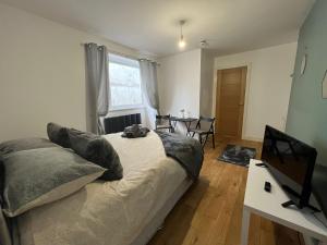a bedroom with a bed and a desk with a television at Dream Weaver Apartment in Swansea