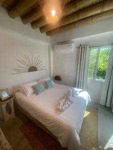 a bedroom with a bed with white sheets and a window at Wander Boutique Hotel in El Paredón Buena Vista