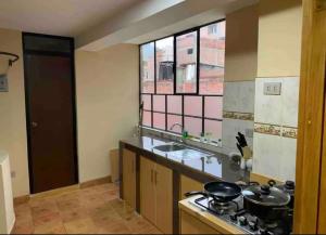 cocina con fogones, fregadero y ventana en Alojamiento a una cuadra de la plaza de armas en Puno