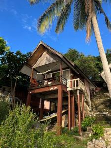 a house with a balcony and a palm tree at Sea Lulaby in Koh Phangan