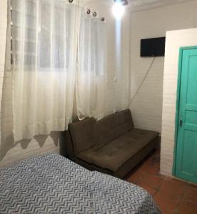 a couch in a room with a window and a bed at Hostel dos Reis in Angra dos Reis