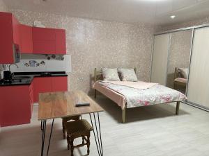 a bedroom with a bed and a table and a kitchen at Днестровский in Kharkiv