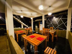 um restaurante com mesas e cadeiras de madeira e luzes em Nice View Safari House em Udawalawe