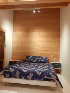 a bedroom with a bed with a wooden wall at Charmant chalet 8p calme et vue sur montagnes in Verchères