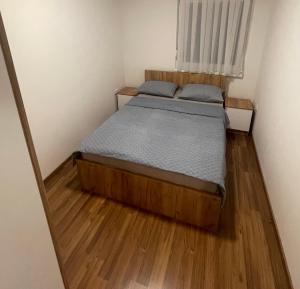 a small bedroom with a bed and wooden floors at Happy Apartment in Prijedor