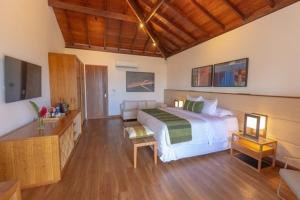 a bedroom with a white bed and a wooden floor at Kûara Hotel in Arraial d'Ajuda