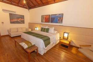 a bedroom with a large bed and a couch at Kûara Hotel in Arraial d'Ajuda