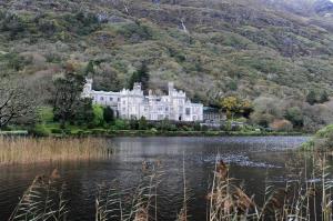 a large white house sitting on the edge of a lake at Lakeside house in Oughterard