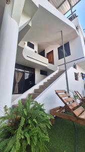 Galápagos Brunette Suites في بويرتو أيورا: بيت ابيض فيه درج ونبات خضراء