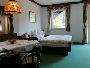 a bedroom with two beds and a table and a window at Hotel garni Landhaus Bürtlmair in Hinterstoder