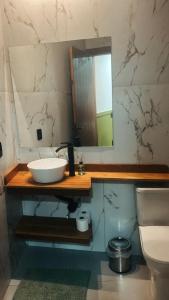 a bathroom with a sink and a mirror and a toilet at Pousada Águas da Grota in Penha
