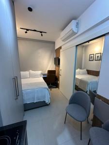 a hotel room with two beds and a chair at MARCOLINI - Flat em frente ao Allianz Parque in Sao Paulo