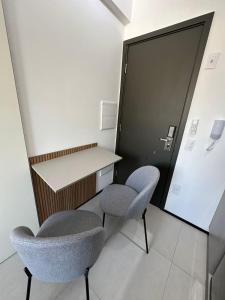 a room with two chairs and a desk and a door at MARCOLINI - Flat em frente ao Allianz Parque in Sao Paulo